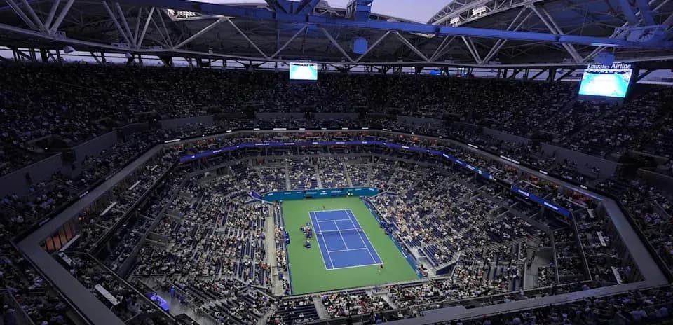 Estadio lleno durante partido de tenis nocturno