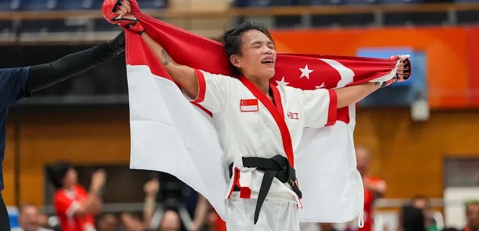 Atleta sosteniendo la bandera de Singapur tras competir