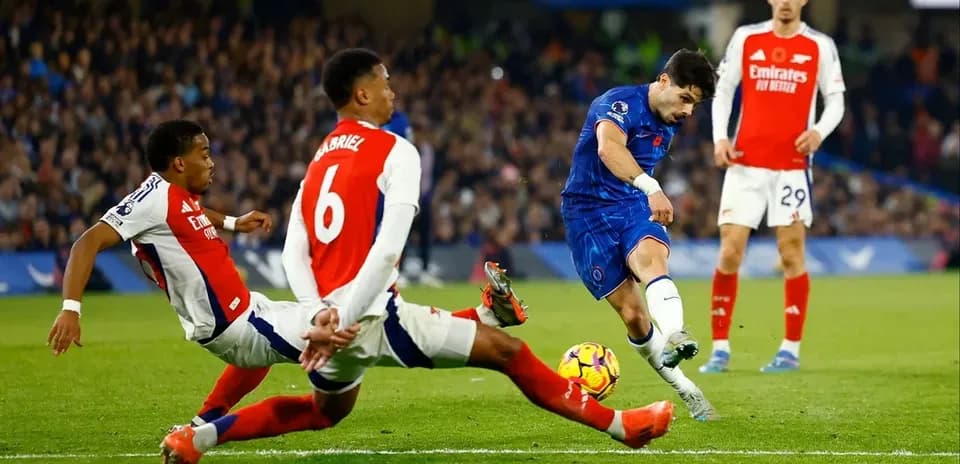 Jugador de Chelsea disparando mientras es defendido por Arsenal