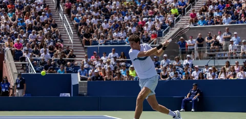 Jugador golpeando una pelota de tenis en el partido