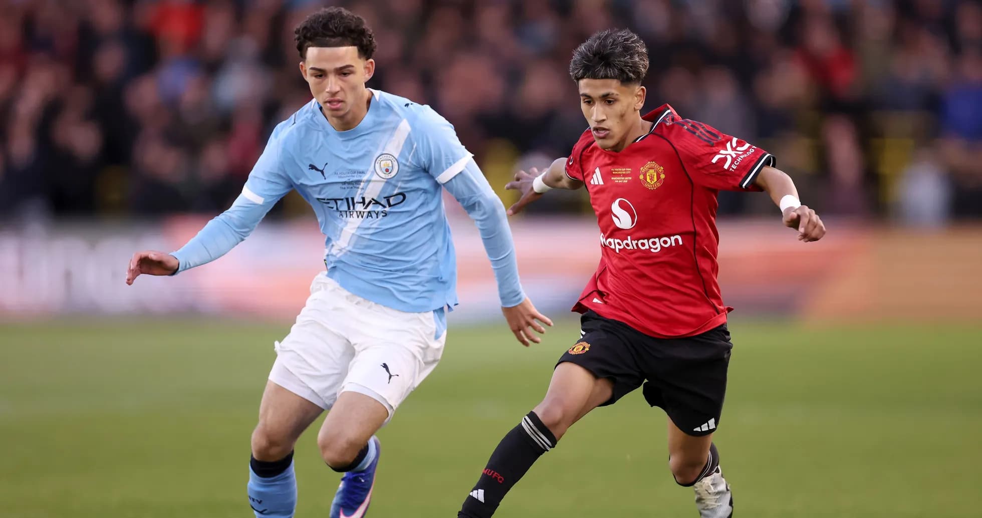 Jugadores de Manchester City y Manchester United corriendo tras el balón