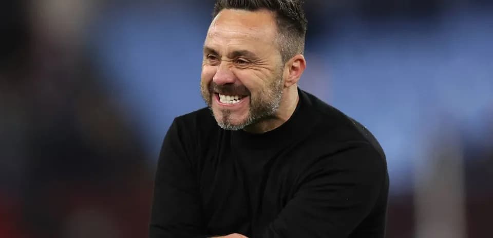 Entrenador sonriendo durante un partido de fútbol