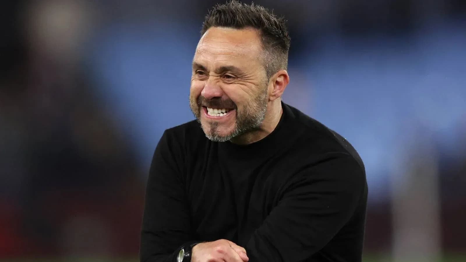 Entrenador sonriendo durante un partido de fútbol