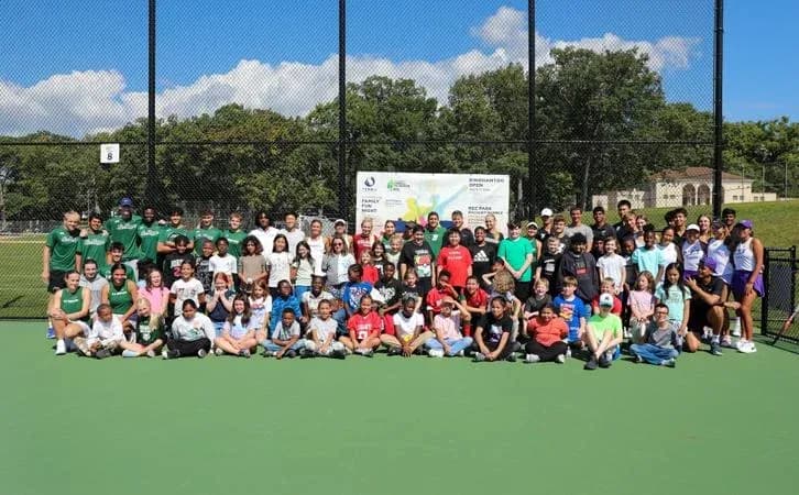 Grupo de personas en cancha de tenis al aire libre