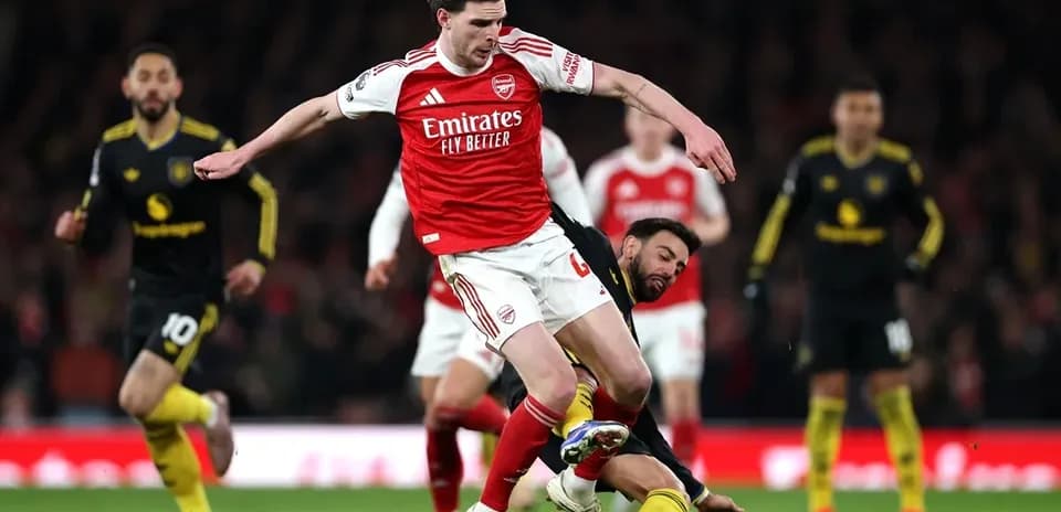 Jugador de Arsenal esquivando a oponente en el suelo