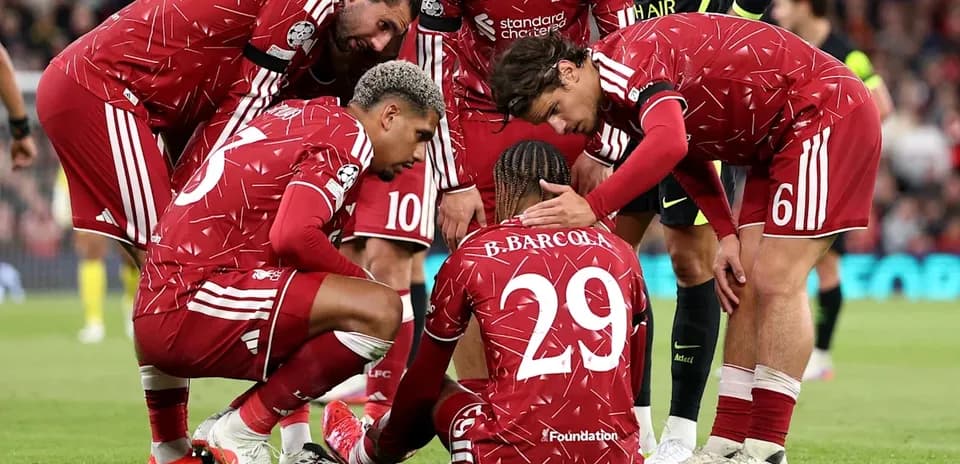 Jugadores de Liverpool rodeando a un compañero caído