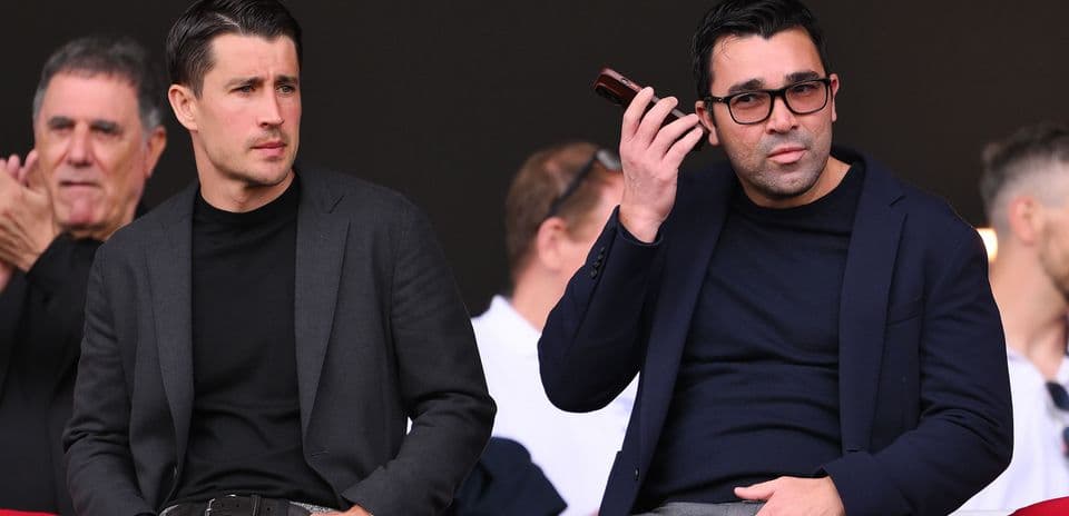 Dos hombres sentados en un palco de estadio