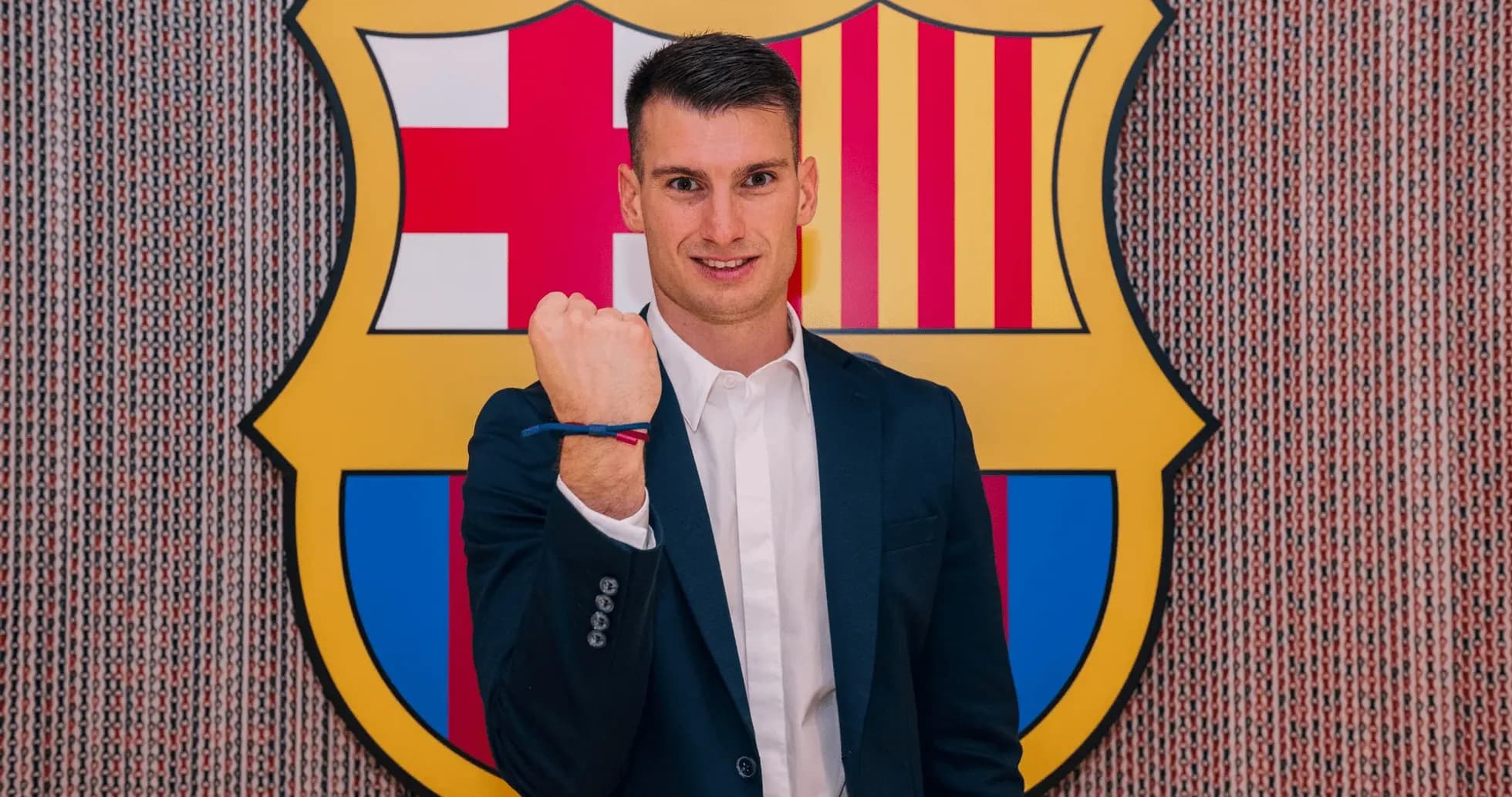 Jugador mostrando el puño frente al escudo del Barcelona