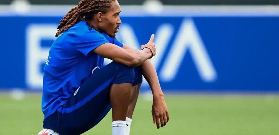 Jugador sentado en el campo con balón de fútbol