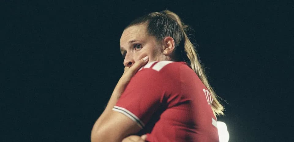 Jugadora con camiseta roja pensativa en el campo
