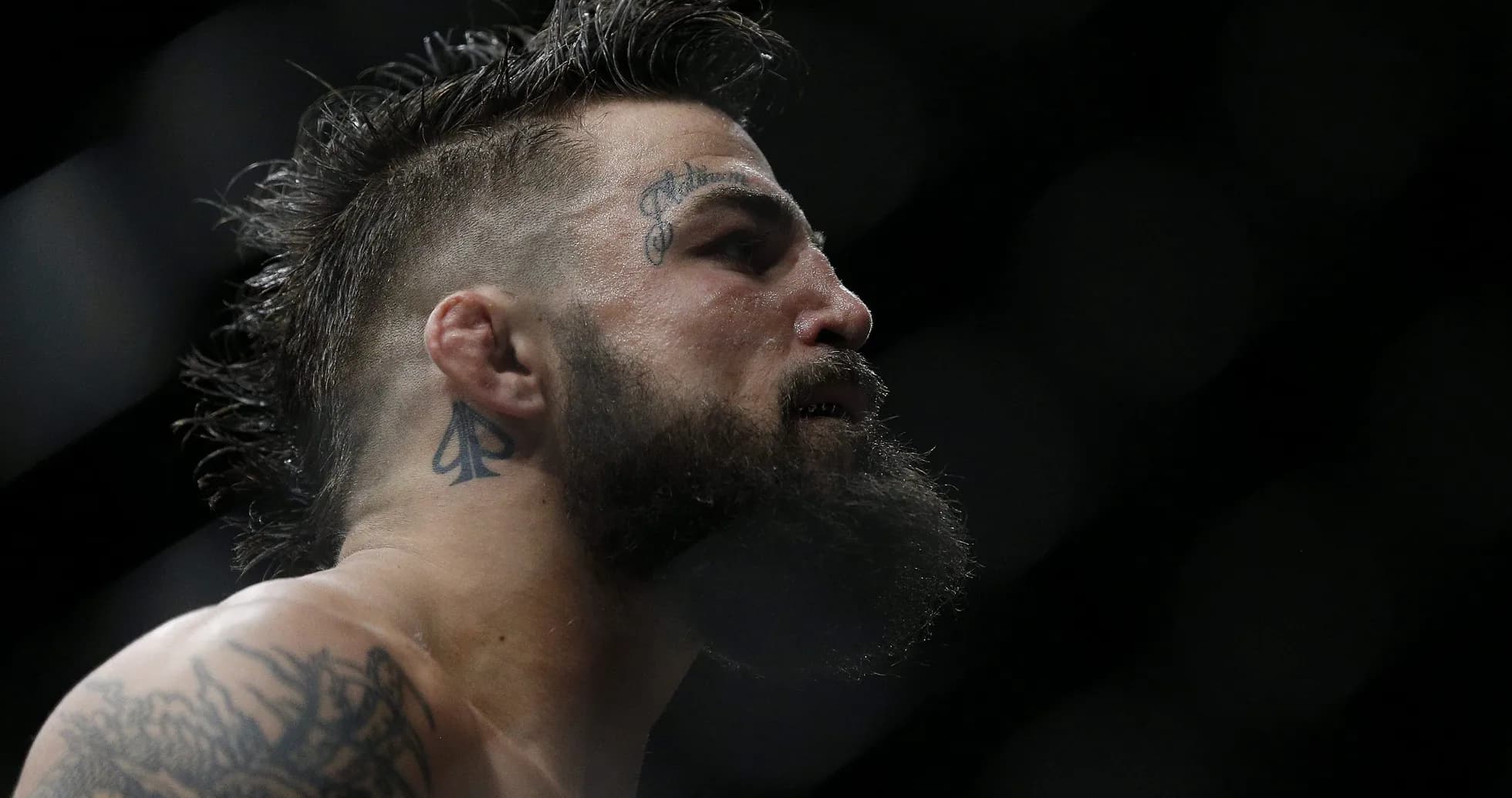 Luchador con tatuajes y barba en el ring