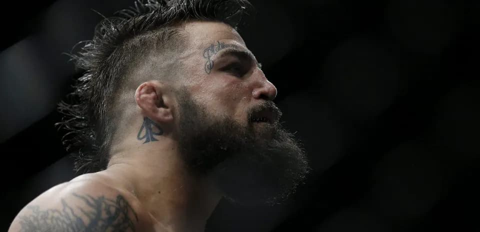 Luchador con tatuajes y barba en el ring