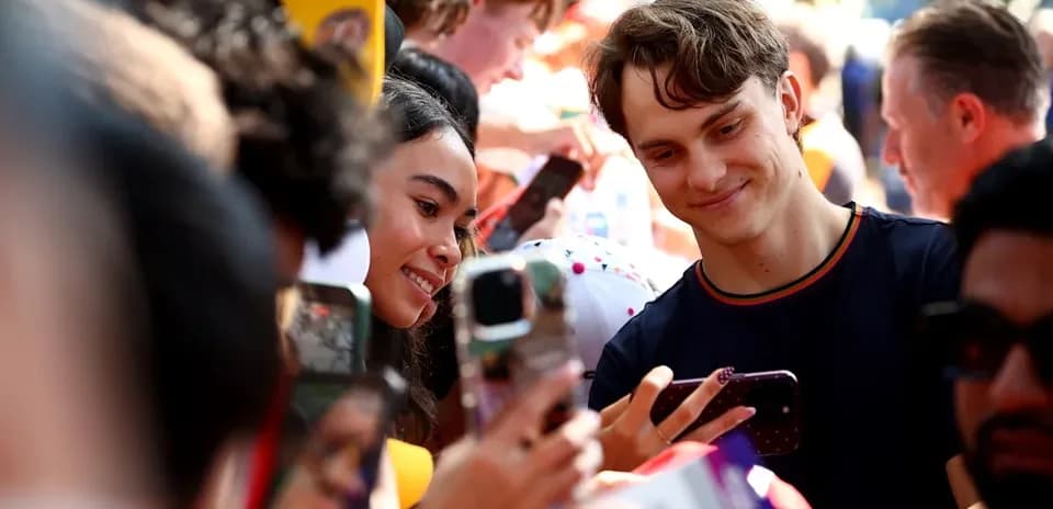 Jovenes sonriendo y usando teléfonos móviles en evento