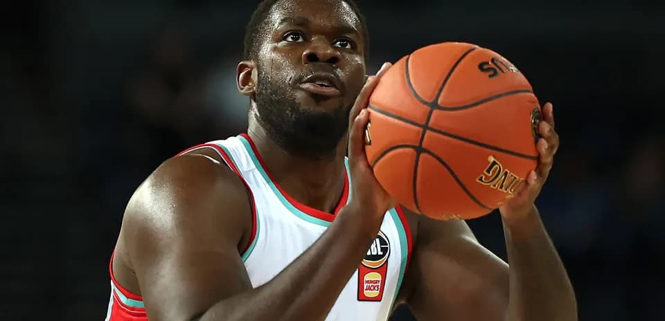 Jugador lanzando balón de baloncesto en partido