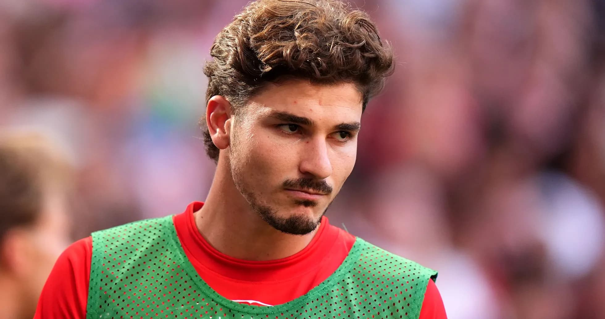 Jugador con camiseta roja y pechera verde en el campo