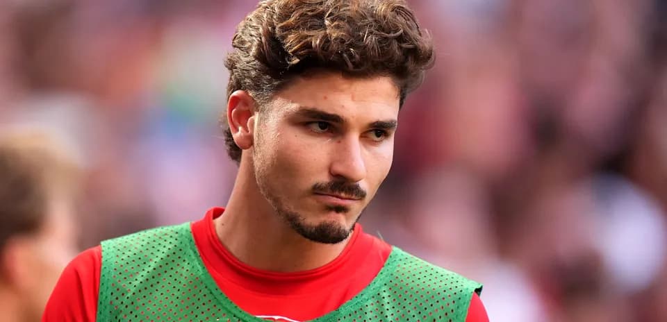 Jugador con camiseta roja y pechera verde en el campo