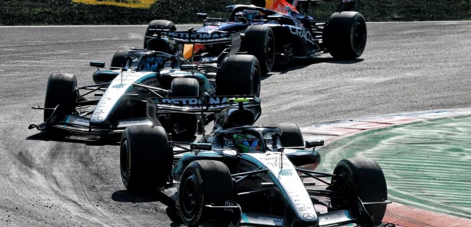 Tres coches de Fórmula 1 compitiendo en la curva
