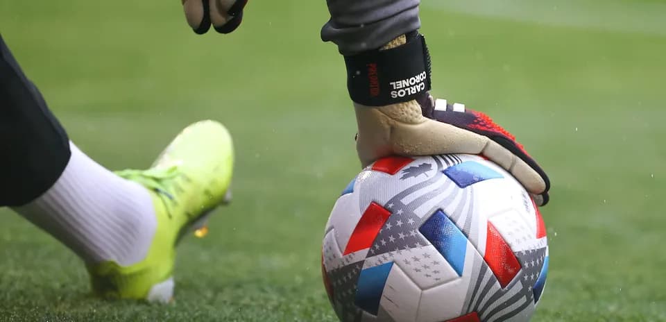 Portero sosteniendo balón de fútbol en el campo