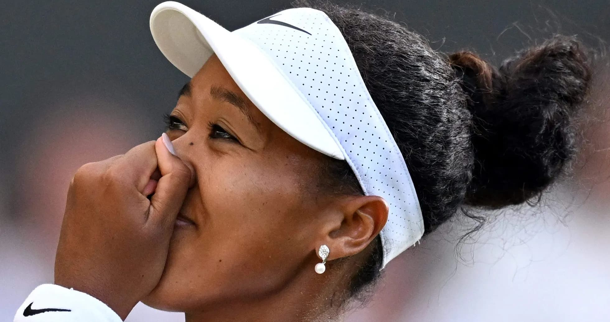 Naomi Osaka con visera y tocando su nariz