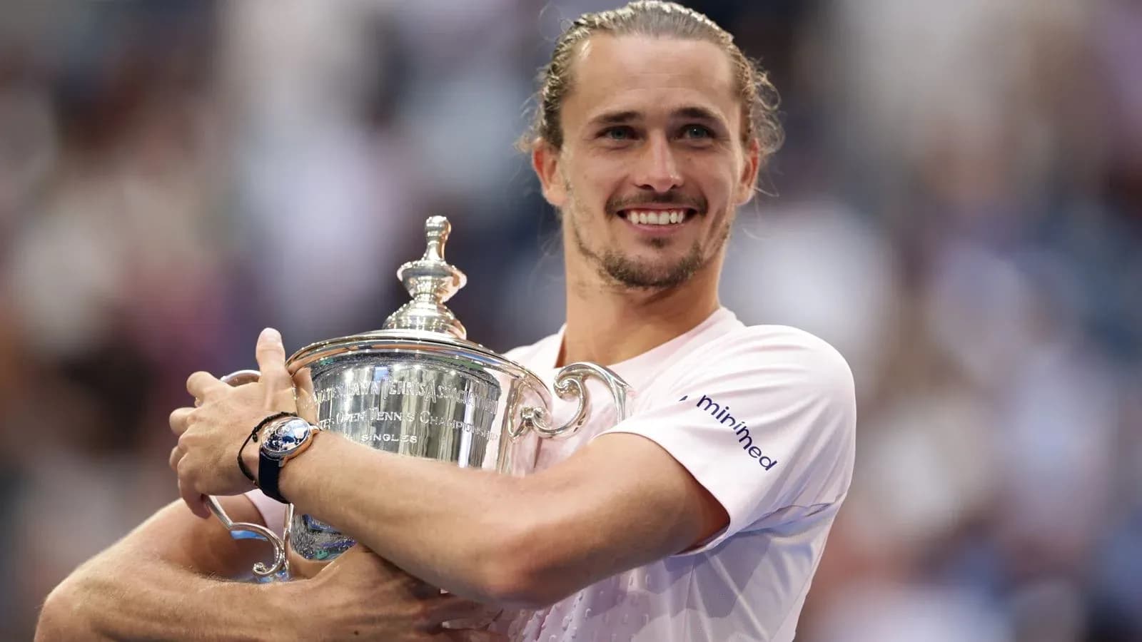 Jugador sosteniendo el trofeo de tenis sonriente