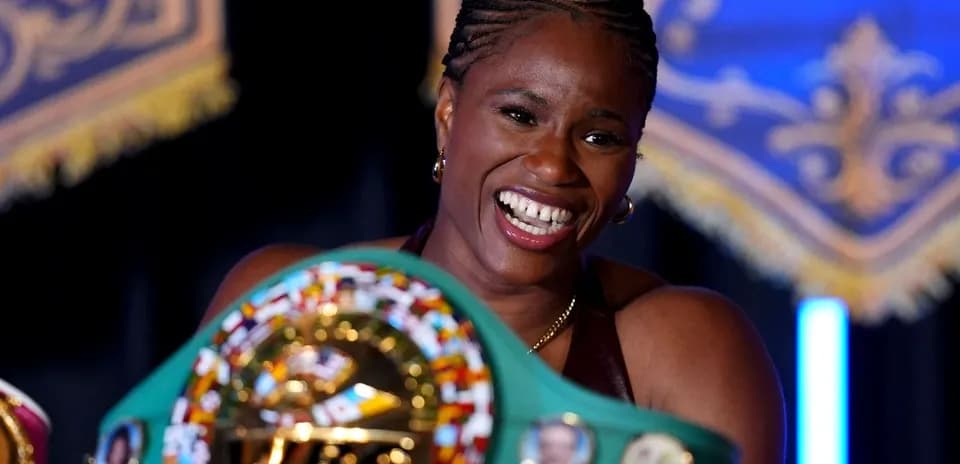 Boxeadora sonriente sosteniendo cinturón de campeonato