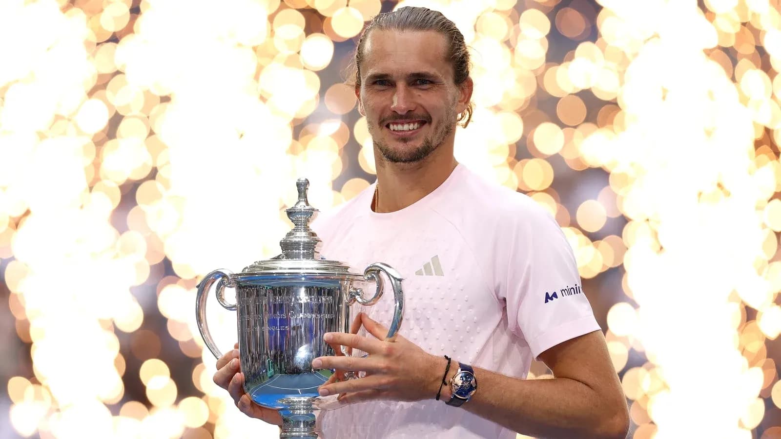 Jugador sosteniendo trofeo de tenis con fondo brillante