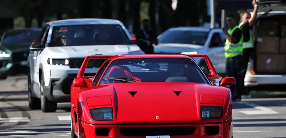 Ferrari rojo circulando entre otros vehículos en la calle