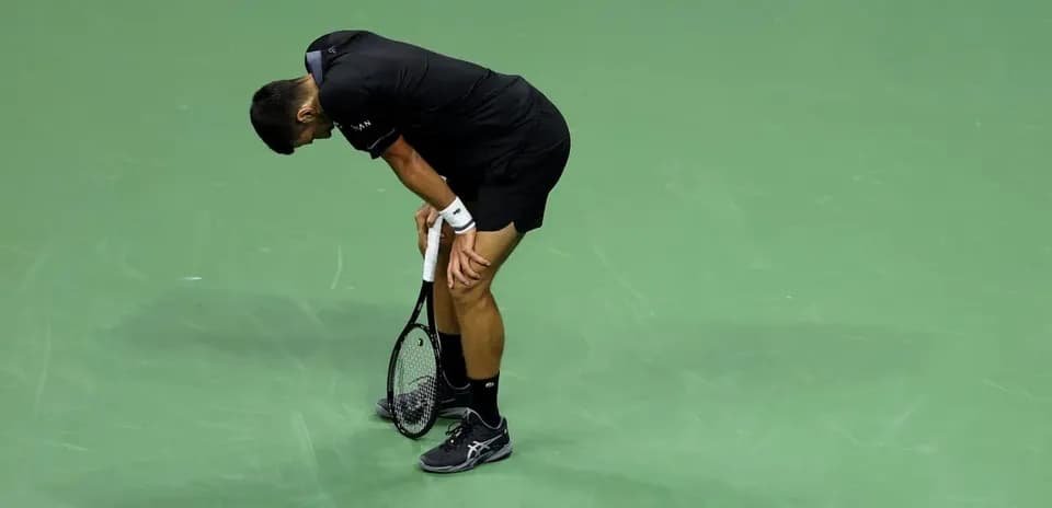 Jugador de tenis inclinado con raqueta en la mano