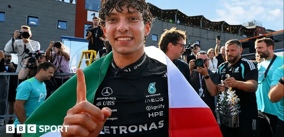 Piloto sosteniendo bandera italiana y trofeo en celebración
