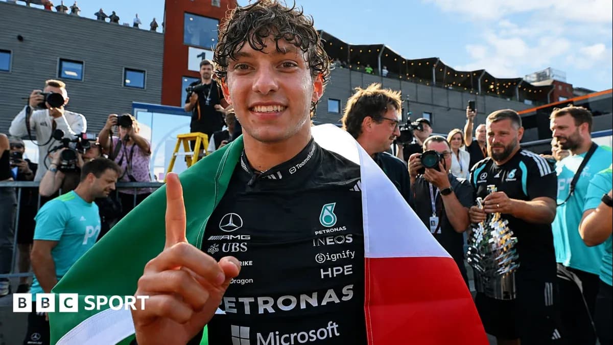 Piloto sosteniendo bandera italiana y trofeo en celebración