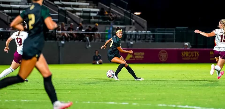 Jugadora pasa el balón en partido de fútbol femenino