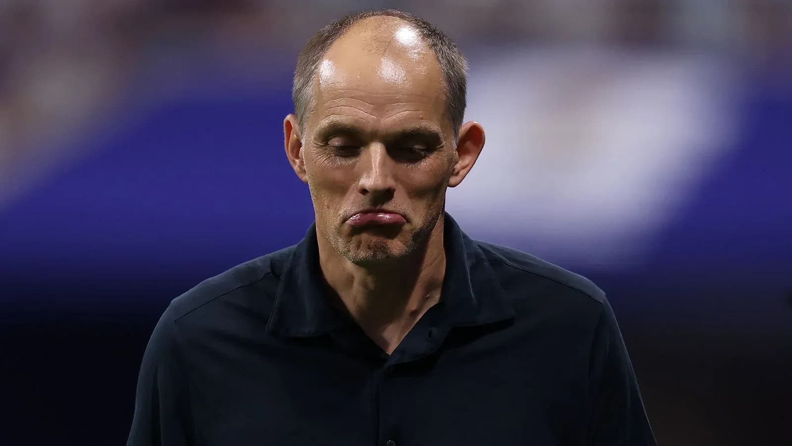 Entrenador caminando con expresión seria durante partido