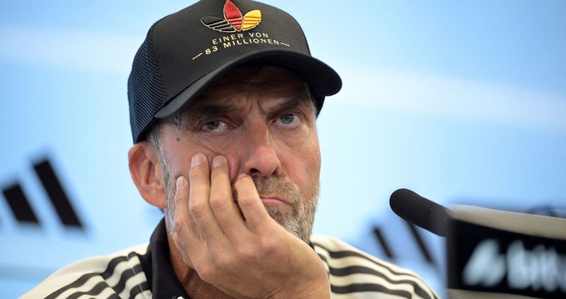 Entrenador en rueda de prensa con expresión pensativa