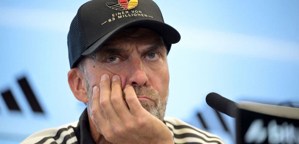 Entrenador en rueda de prensa con expresión pensativa