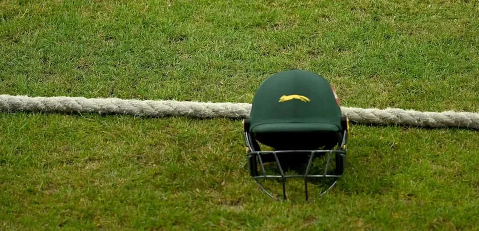 Casco de cricket en el césped junto a cuerda