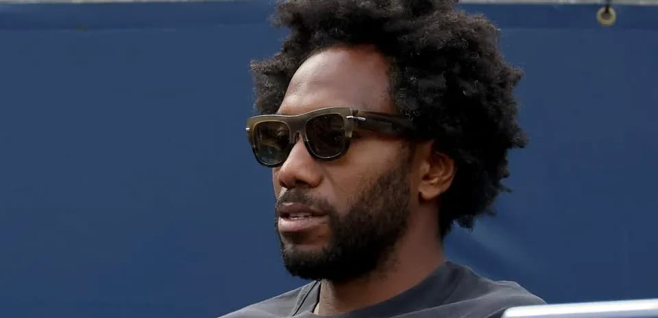 Hombre con gafas oscuras sentado en la grada