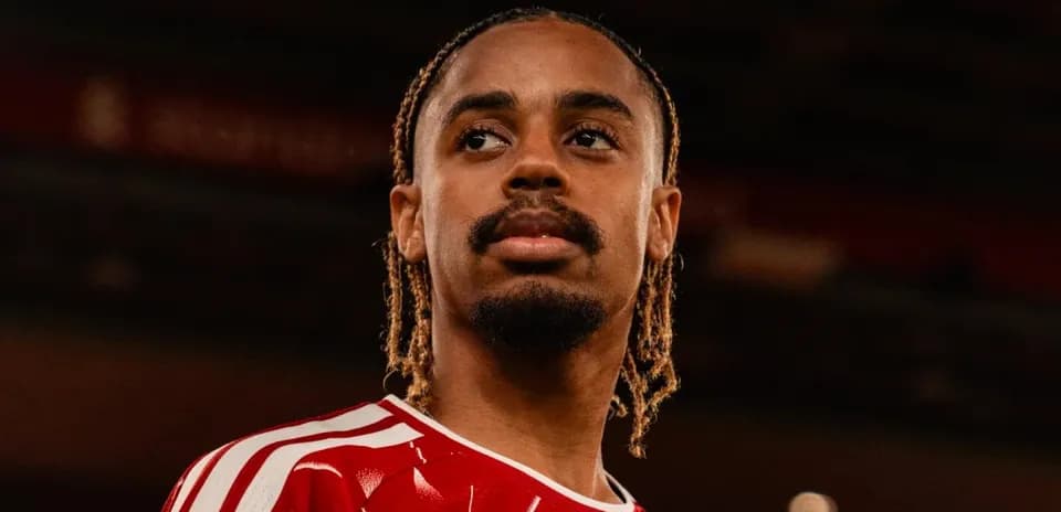 Jugador posando con camiseta roja en estadio