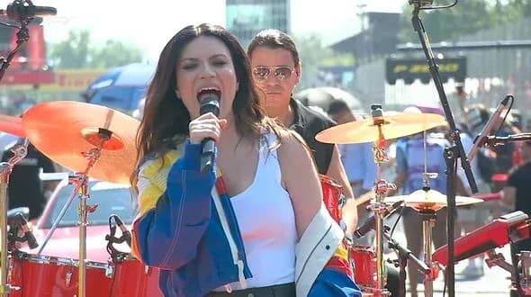 Cantante actuando con banda en evento al aire libre