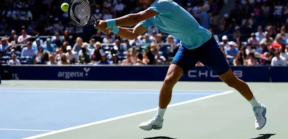 Jugador alcanzando la pelota durante un partido de tenis