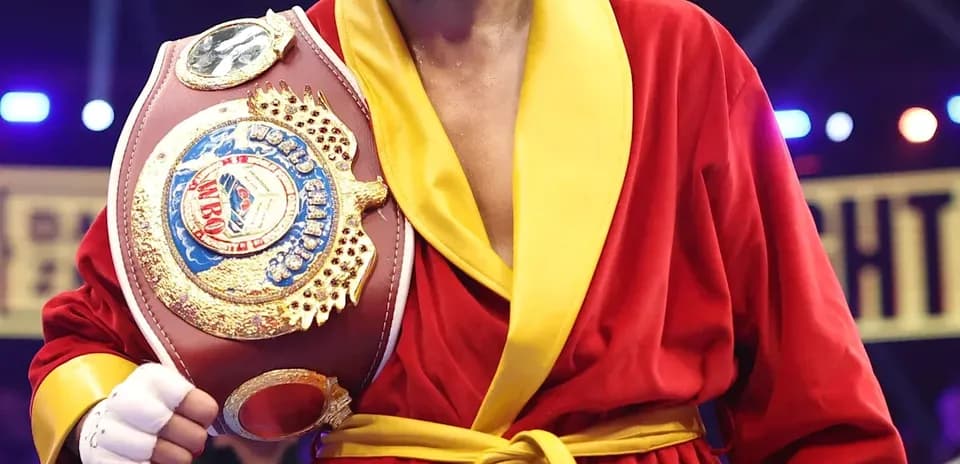 Boxeador con cinturón en bata roja y amarilla