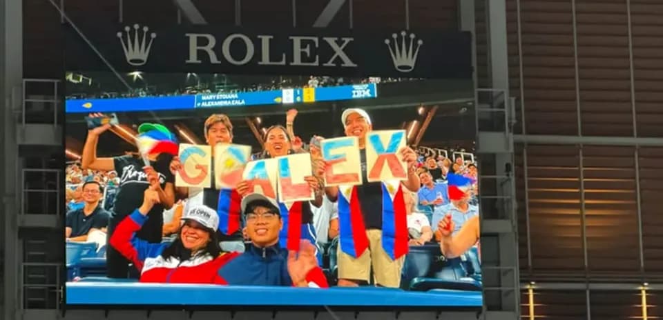 Aficionados sosteniendo cartel que dice 'GO ALEX'