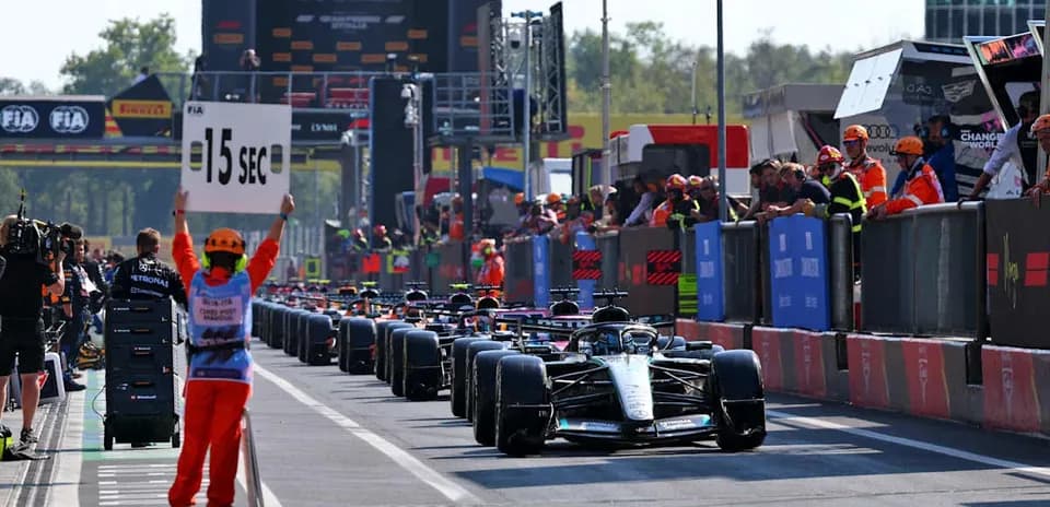 Pilotos de Fórmula 1 en pit lane con señal de penalización
