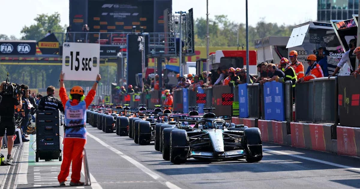Pilotos de Fórmula 1 en pit lane con señal de penalización