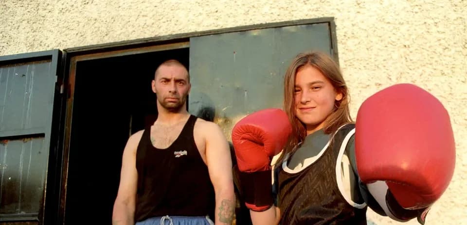 Niña boxeadora con guantes rojos y entrenador