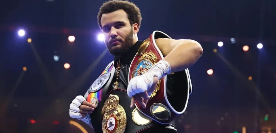Boxeador sosteniendo varios cinturones de campeón