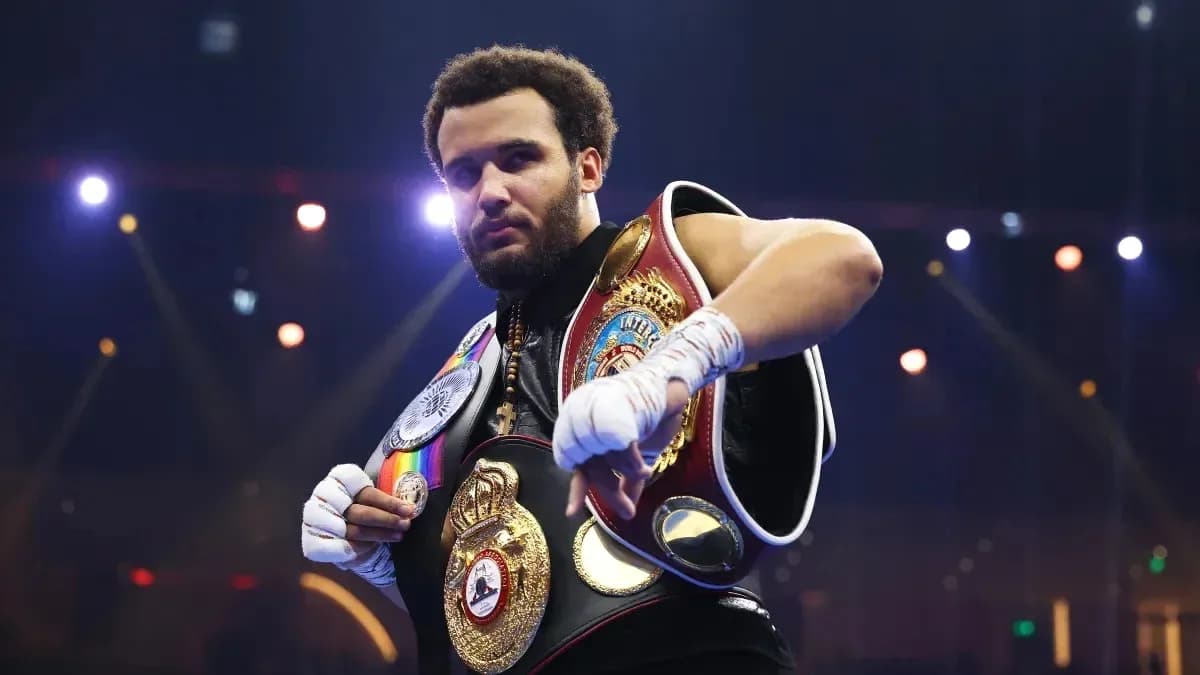 Boxeador sosteniendo varios cinturones de campeón
