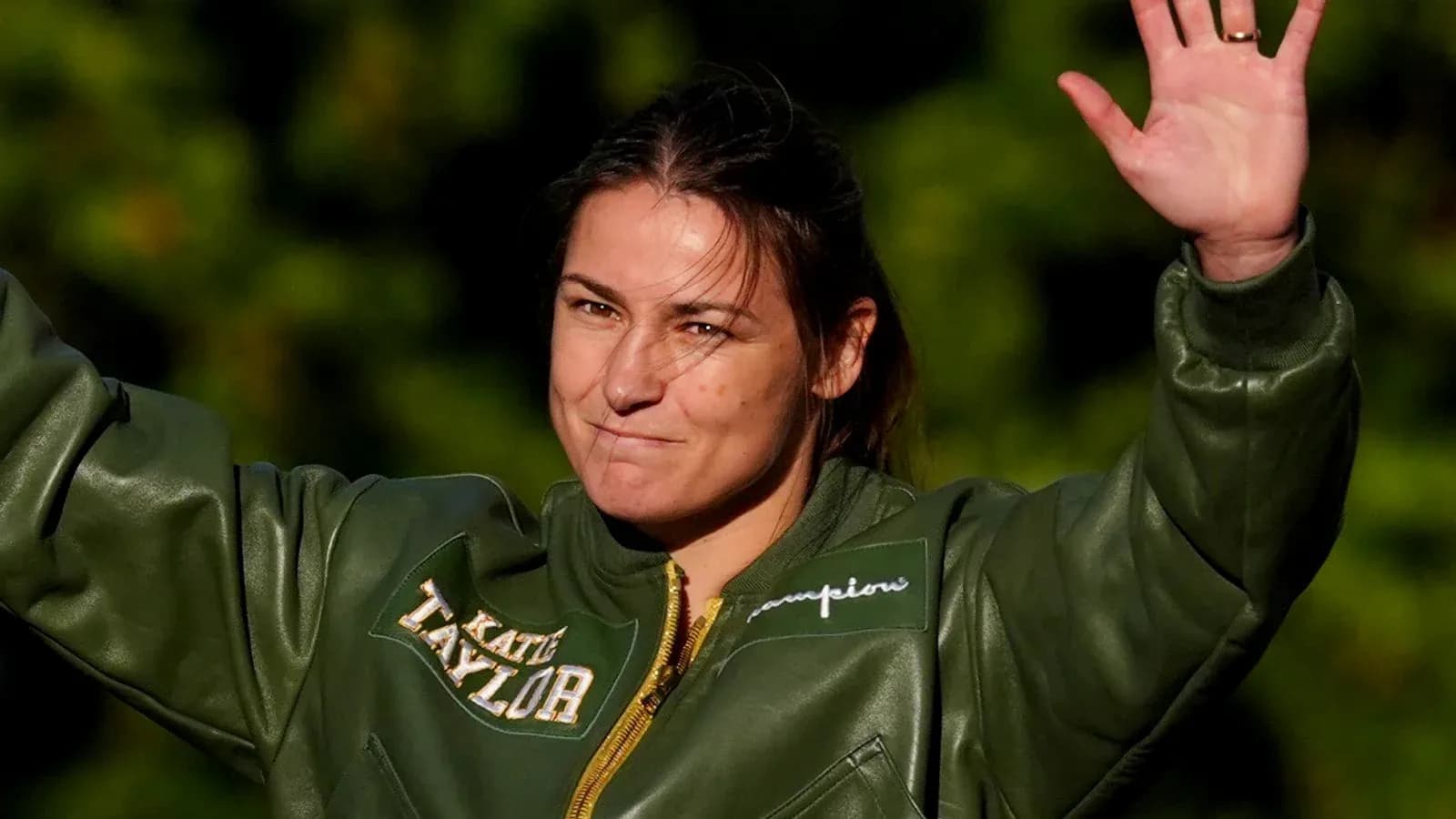 Deportista saludando con chaqueta verde en exterior Deportista saludando con chaqueta verde en exterior