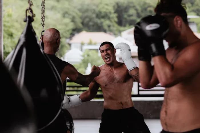 Boxeadores entrenando en gimnasio con sacos de boxeo Boxeadores entrenando en gimnasio con sacos de boxeo