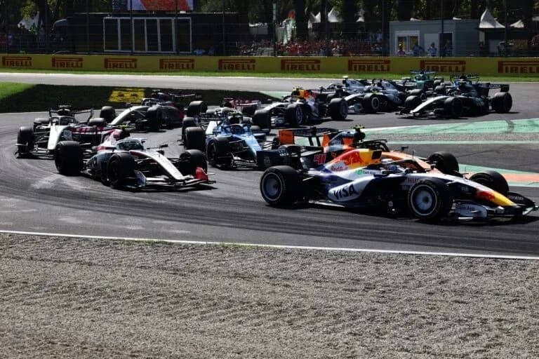 Varios coches de Fórmula 1 compitiendo en curva Varios coches de Fórmula 1 compitiendo en curva