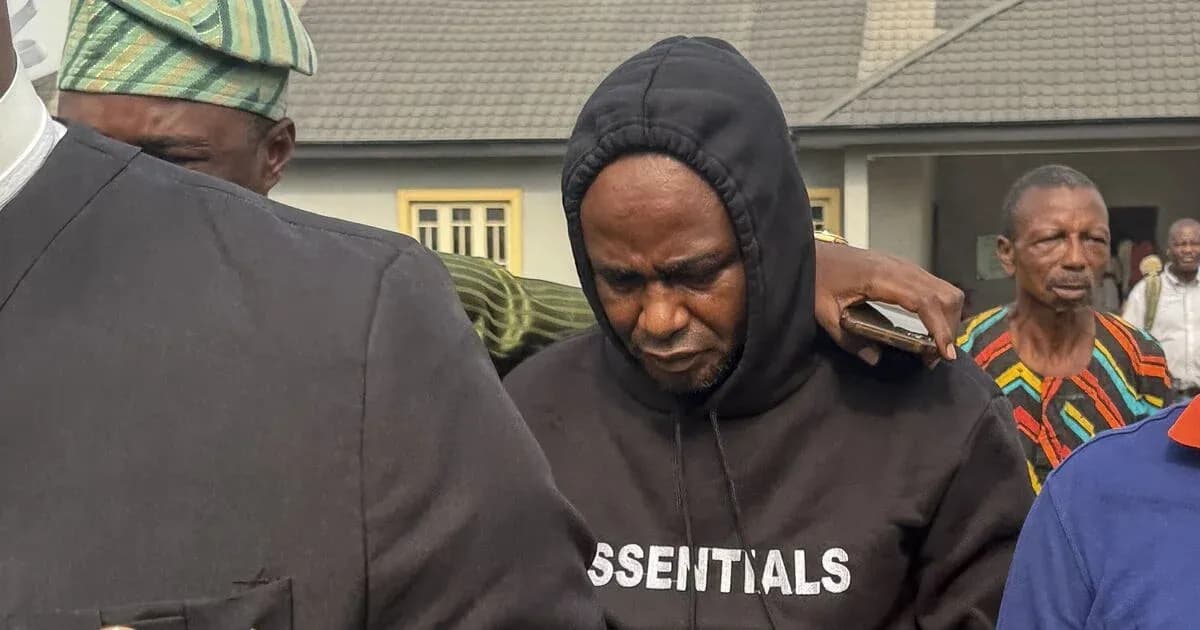 Hombre con sudadera negra rodeado de personas en un evento Hombre con sudadera negra rodeado de personas en un evento
